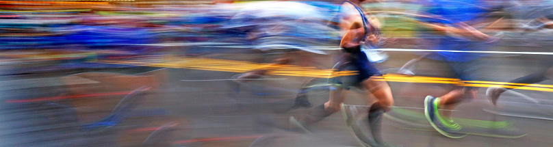 The blurred motion of marathon runners as they compete on an urban street.