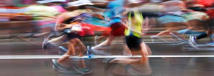 The blurred motion of marathon runners as they compete on an urban street.
