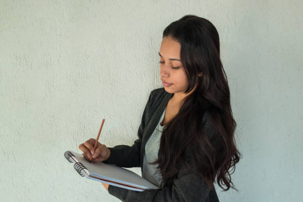 istock A charming young entrepreneur taking notes in a notebook smiling on a white background 1256934896