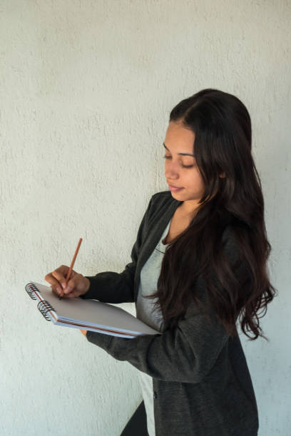 istock A beautiful Hispanic woman at home writing notes while holding a notebook. 1256934906