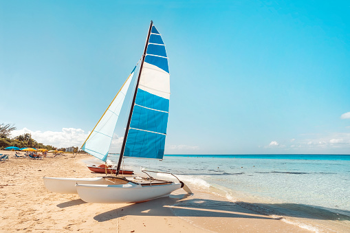 A sailing catamaran is parked on the white sand on the seashore against the backdrop of beautiful tropical nature. tourist attractions in Cuba.