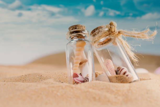 istock sandy beach and shells in two glass jar on sand and summer beach 1256940814