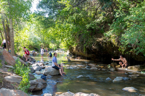 Crowd of People Enjoying Dripping Rock Falls/Hike on a Summer Afternoon July 18, 2020 - Spanish Fork, Utah, USA: This group of people are enjoying the refreshing river along the Dripping Rock Hike.  Along the river are small caves or grottos surrounded by streams of water dripping down into the river.  This shot was taken on a hot summer afternoon. spanish fork utah stock pictures, royalty-free photos & images