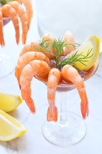 Cooked shrimp with cocktail sauce against a granite tabletop.  Shellfish like shrimp are a delicious appetizer but also pose a health risk to anyone with a food allergy to shellfish.