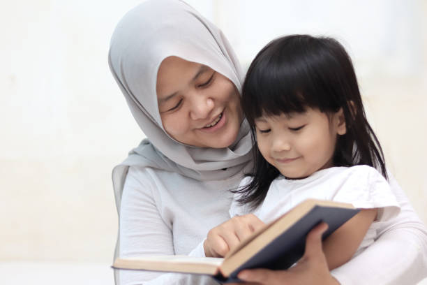 muslim mother teach her daughter how to read the holy quran - east asian ethnicity imagens e fotografias de stock