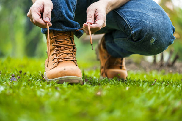 Man kneel down and tie shoes industry boots for worker. Close up shot of man hands tied shoestring for his construction brown boots.  Close up man hands tie up shoes for footwear concept. Man kneel down and tie shoes industry boots for worker. Close up shot of man hands tied shoestring for his construction brown boots.  Close up man hands tie up shoes for footwear concept. lace up stock pictures, royalty-free photos & images