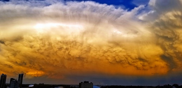Humongous cellular mammatus and cumulonimbus stormclouds ominously hoovering over the city of Calgary during sunset!