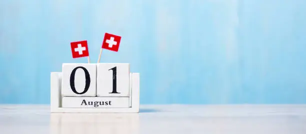 Photo of Wooden calendar of August 1st with miniature Switzerland flags. Swiss National Day and happy celebration concepts