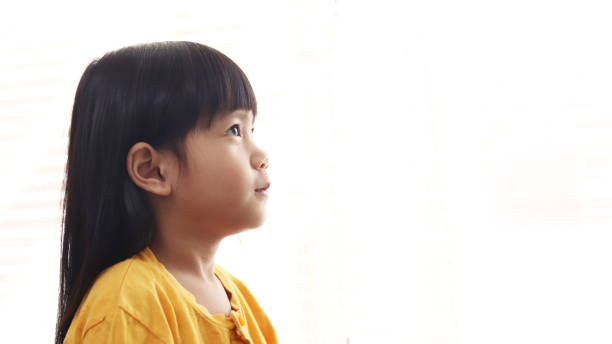 симпатичные маленькие азиатские девочки глядя мышления что-то изолированное на белом фоне, боковой профиль. надежда концепции - one baby girl only фотографии стоковые фото и изображения