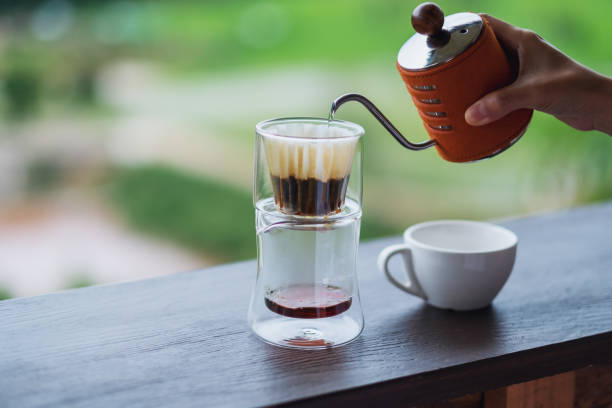 istock a hand pouring hot water from kettle to make drip coffee with blurred nature background 1256962127