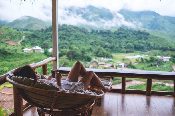istock a woman holding coffee cup while lying on sofa on balcony , looking at mountains and green nature 1256962152