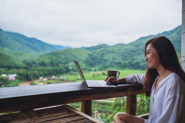 istock a woman working and typing on laptop computer while sitting on balcony with mountains and green nature background 1256962154