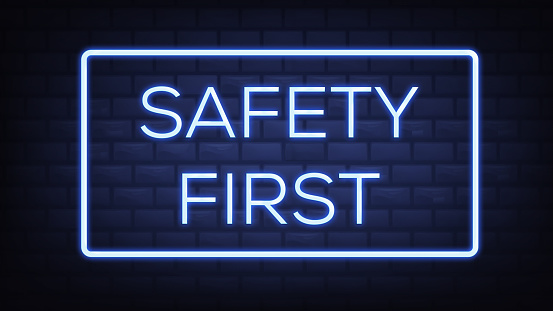 Safety First neon text on brick wall background