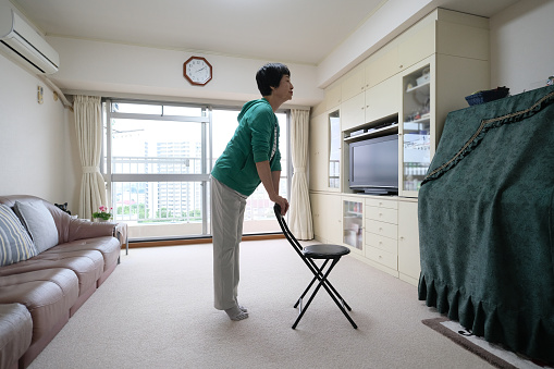 Asian senior woman exercising at home with chair