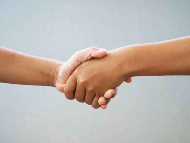 istock Two male hands shaking isolated on blue studio background. Social concepts. 1256965189