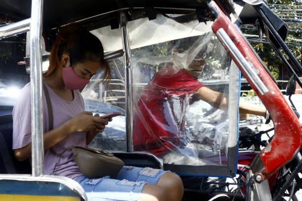 Filipina with face mask in a tricycle with plastic barrier during the Covid 19 outbreak Antipolo City, Philippines - July 16, 2020: Filipina wearing face mask ride a tricycle with plastic barrier for social distancing during the Covid 19 outbreak. philippines tricycle stock pictures, royalty-free photos & images