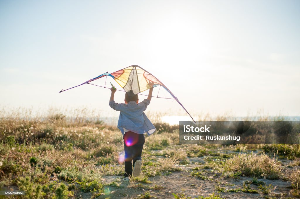 brave new world concept of little active sport boy running with kite above his head towards sunset sea horizon brave new world concept of little active boy running with kite above his head towards sunset sea horizon Aircraft Wing Stock Photo