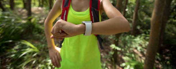 istock Young woman trail runner  looking at her smartwatch while running in tropical forest 1256980611