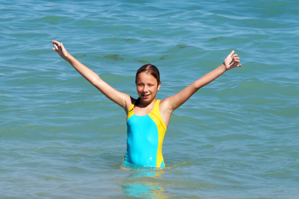 istock girl with hands up smiling at sea 1256983257