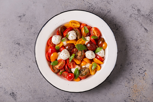 Traditional Caprese salad made of sliced fresh tomatoes, mozzarella cheese and basil, top view