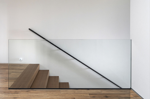 Element of modern interior design with hardwood stairs and glass fence against white copy space wall