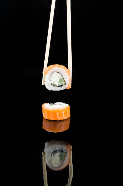 istock chopsticks  taking  sushi philadelphia with salmon on black background. 1256986787