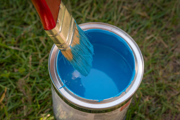 istock woman's hand dips a brush into a jar of blue paint close up 1256990052