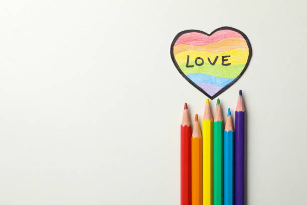 Colored pencils and LGBT heart on white background, space for text