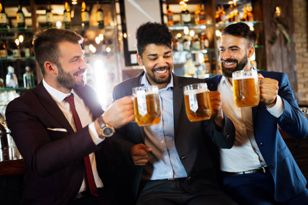 istock Happy young businessmen drinking beer and talking at pub after work 1256991778