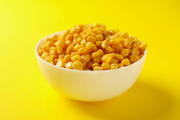 istock Bowl of fresh corn on yellow background, close up 1256993928
