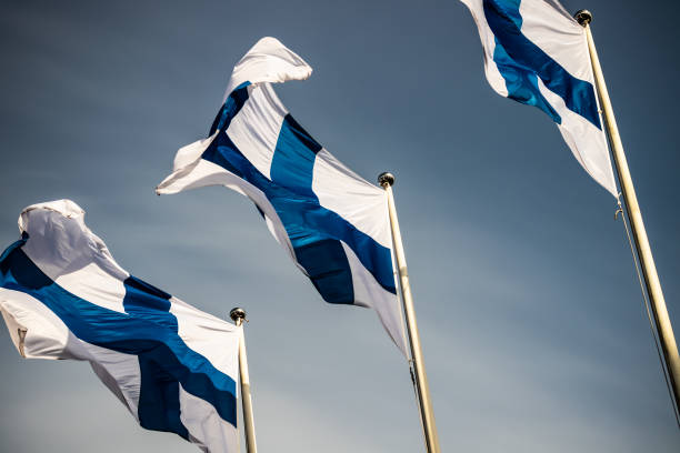 istock Three finnish national flags on the wind against the blue sky 1256995668