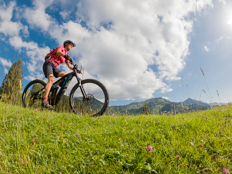 active senior woman riding her electric mountain bike in the Allgau Alps near city of Immenstadt, Allgäu, Bavaria, Germany