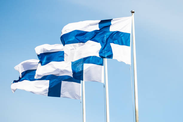 istock Three finnish national flags on the wind against the blue sky 1256997445