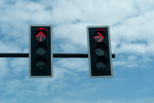 Twin traffic lights under the blue sky. Direct way, red light and turn right, green light