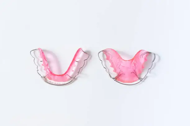 Photo of hawley retainer on white background. pink retainer teeths for dental patient.