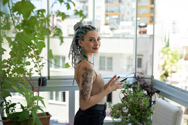 jeune femme utilisant le téléphone dans le balcon - tatouage femme photos et images de collection