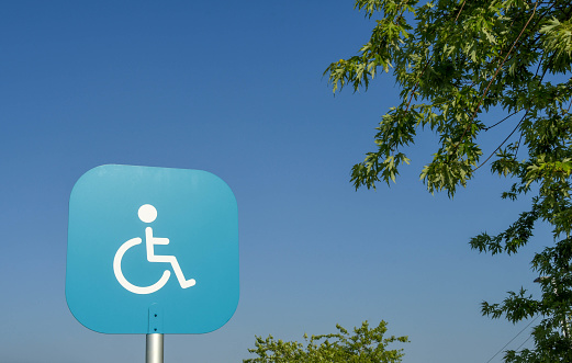 Sign with a wheelchair symbol on a plain blue background marking a car parking bay reserved for disabled persons. No people.