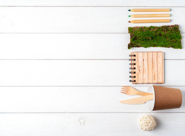 istock Glass jar, green leaves, notebook and recycled tableware top view. Flat lay Zero waste, eco friendly, natural organic plastic free concept. Cutlery, earth, biodegradable with copy space on white wood 1257007761