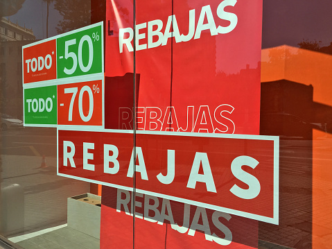 Valencia, Spain - July 18, 2020: Lots of colorful signs advertising sales up to 70 percent in store window. During the months of july and august there are lots of discounts because of the change of season