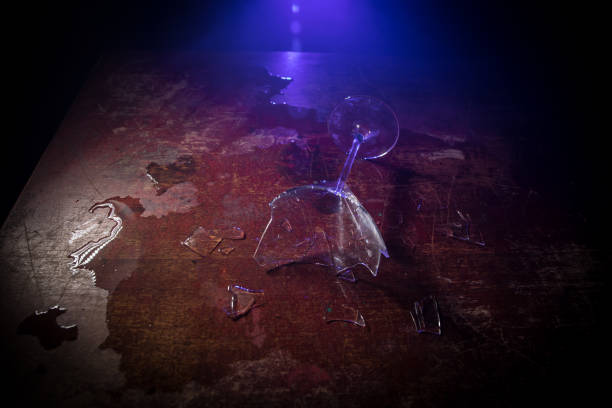istock Broken glasses on wooden table at dark toned background with fog. Selective focus 1257008613