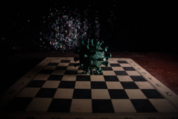 istock Big Corona virus miniature model on chessboard with fog and backlight. Creative artwork decoration. Selective focus 1257010100