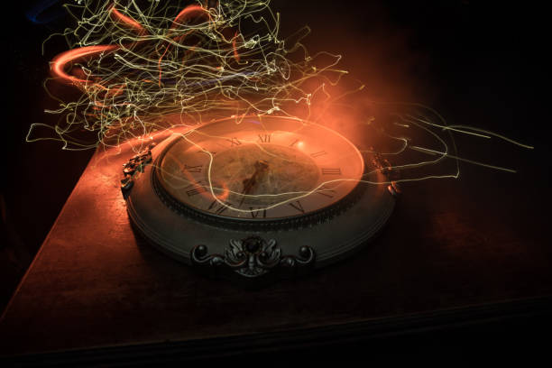 Time concept. Big vintage round clock on wooden table with abstract light.