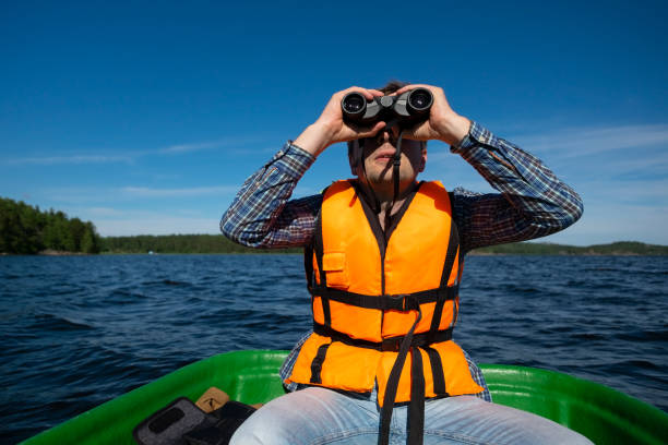 istock Man in the boat looks in the binoculars 1257012227