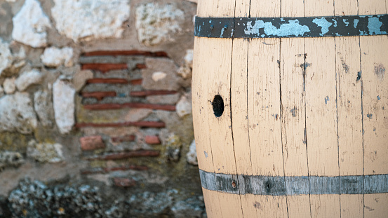An old brown wine barrel sitting in a courtyard against a stone wall