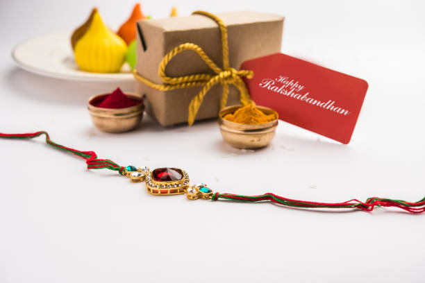 Indian festival Raksha Bandhan with rakhi bracelets, presents, rice and kumkum in bowls. Copy space Raksha Bandhan / Rakshabandhan Rakhi with Haldi Kumkum rice, sweet Mithai, Gift Box, selective focus rakhi stock pictures, royalty-free photos & images