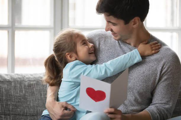istock Little daughter greeting excited young father with postcard 1257016172