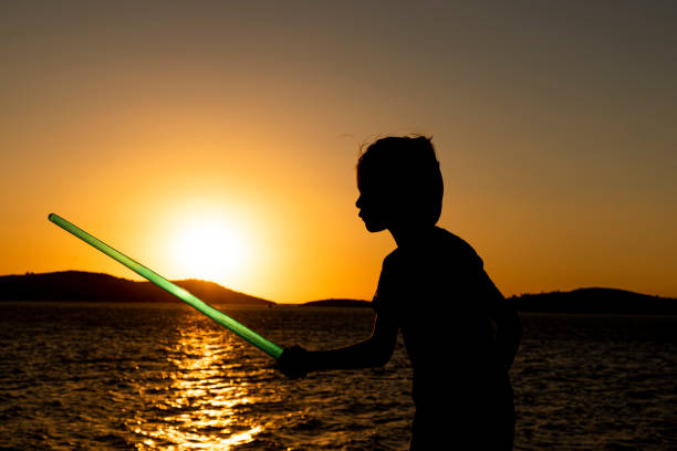little boy playing with sword on the beach