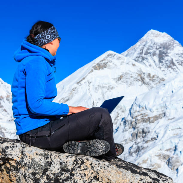istock Woman is using laptop in Himalayas, Mount Everest on background 1257018417