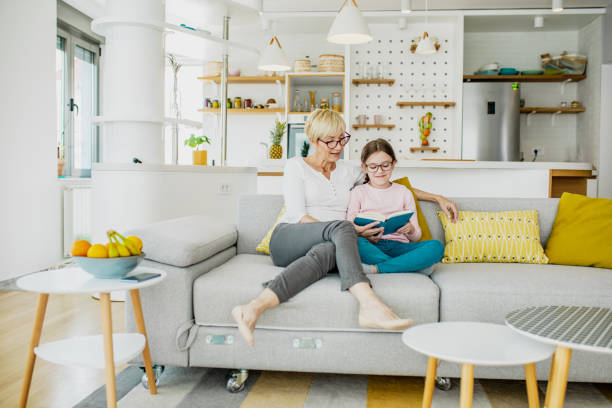 istock A grandmother and granddaughter reading on sofa 1257018527