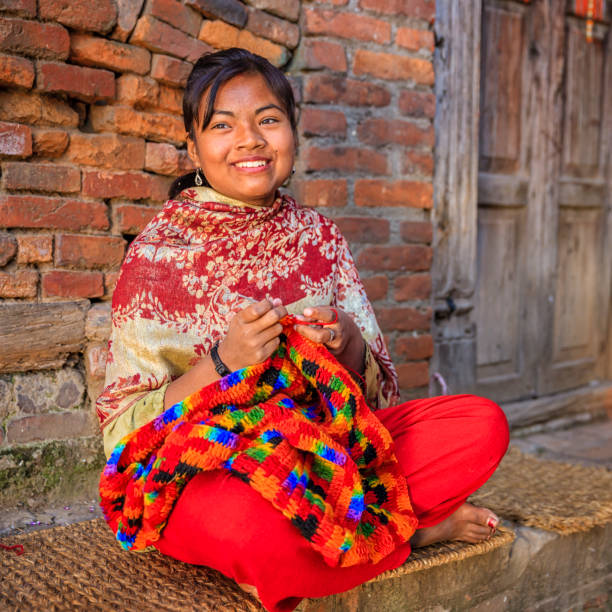 Nepali young woman  kniting a wool scarf in Bhaktapur. Nepali woman kniting a wool scarf in front of the house. Bhaktapur in Kathmandu valley. Nepal. patan durbar square stock pictures, royalty-free photos & images